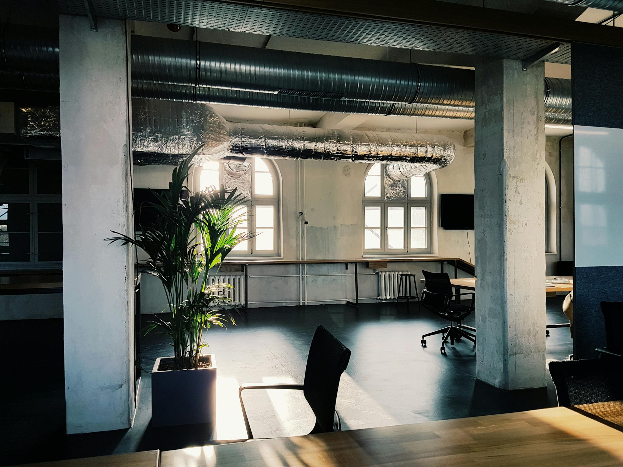 Bright modern office interior with industrial design elements and natural light through large windows.